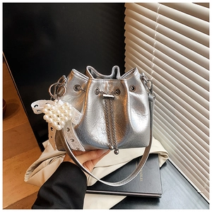 Detail of silver drawstring bucket bag with pearl heart charm and metallic finish