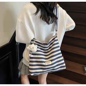 Detail of blue striped canvas tote bag with shoulder strap and fluffy cloud charm