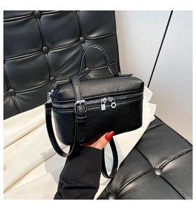 Detail of black litchi grain leather box bag with silver hardware and top handle