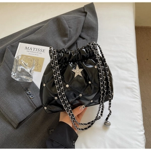 Détail du sac seau noir matelassé avec étoile argentée et ornements de clous