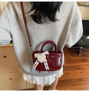 Sac fourre-tout en cuir verni bordeaux porté en bandoulière avec nœud et perles
