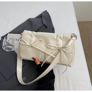 Détail du sac à bandoulière en similicuir crème avec texture plissée et deux nœuds