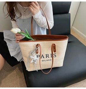 Detail of woven beige tote bag with PARIS MILANO embroidery and silver star charm