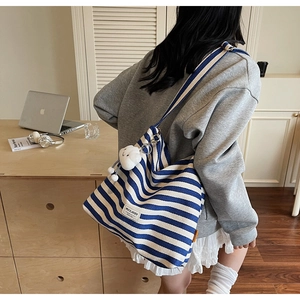 Detail of blue striped canvas tote bag with brand label and plush cloud pendant