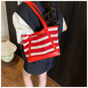 Detailed back view of a large red and white striped tote bag worn by a model