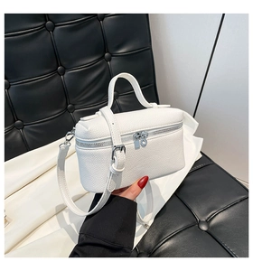 Close-up of white lychee pattern leather handbag with silver zippers and top handle