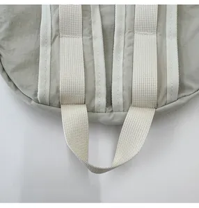 Close-up of the beige nylon drawstring backpack with durable webbing handle and neat stitching