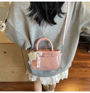 Détail du sac seau en cuir souple rose avec pendentif coeur en perles et dentelle