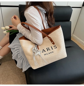 Detailed view of cream straw tote with leather straps and Paris Milano lettering