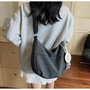 Detailed view of grey denim hobo bag with adjustable wide strap and capybara charm