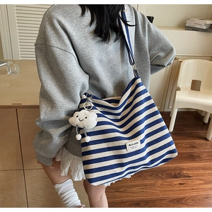 Detail of blue and white striped canvas tote with a cute plush cloud charm
