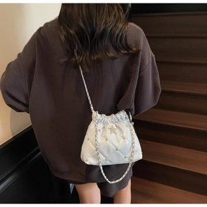 Sac seau matelassé bleu clair avec rivets étoiles et bandoulière sur le mannequin