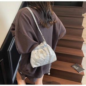 Détail du sac seau matelassé bleu clair avec étoile en métal et fermeture à cordon