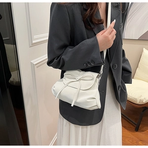 Detailansicht einer weißen Umhängetasche mit stilvollem Schleifenknoten und Faltenleder