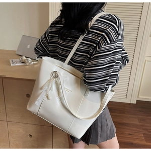 White faux leather tote bag with lace pearl pendant shown on shoulder for daily commute