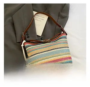 Detail showing colorful woven straw bucket bag with brown leather base and floral charm