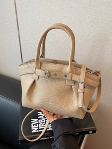 Beige lychee leather handbag with pleated texture and adjustable crossbody shoulder strap