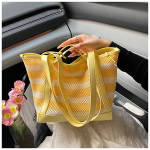 Detail of yellow and white striped mesh tote with premium faux leather handles in car setting