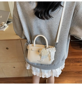 Détail du sac seau en cuir souple avec pendentif cœur en perles et ruban en dentelle