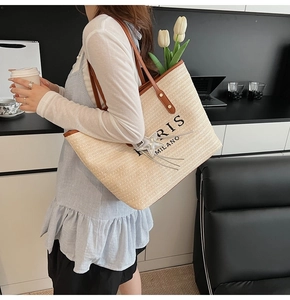 Detail of woven tote bag with leather straps and Paris Milano text in a lifestyle setting