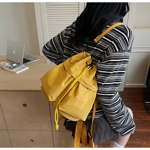 Macro detail of yellow drawstring bucket bag with side pocket in casual urban style
