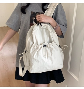 Detail of white drawstring nylon backpack featuring spacious front pocket and double zippers