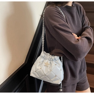 Détail du sac seau matelassé bleu clair avec décor en cristal d'étoile sur modèle