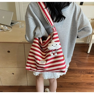 Detail of red and white striped canvas tote bag featuring a cute plush cloud pendant