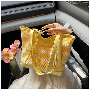 Detail of yellow and white striped mesh tote bag featuring durable PU leather straps