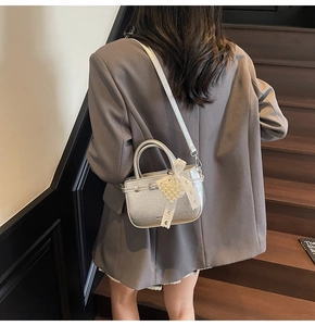 Détail du sac à main argenté avec breloque cœur perlé et nœud en dentelle sur mannequin