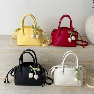 Glossy bucket bags in yellow, red, black, and white colors with tulip charms on marble stairs