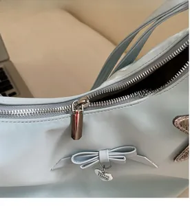 Detail of light blue nylon bag featuring heart pendant and bow decoration close-up