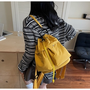 Detail of bright yellow drawstring backpack made of waterproof nylon with side pocket