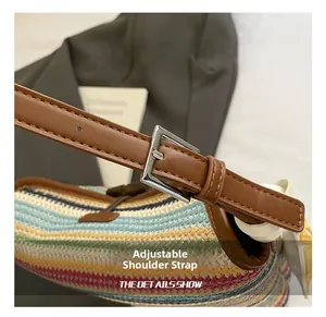 Close-up of the adjustable dark brown leather shoulder strap on a woven straw tote bag
