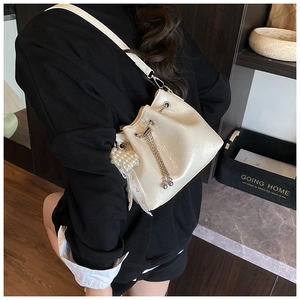 Detail of cream bucket bag featuring pearl heart charm and silver chain accents