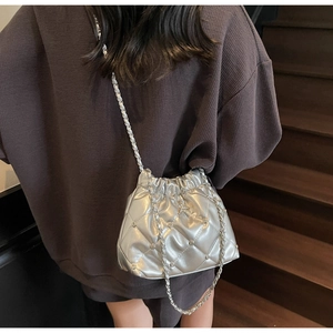 Sac seau matelassé argenté avec décoration étoile et bandoulière chaîne porté à l'épaule