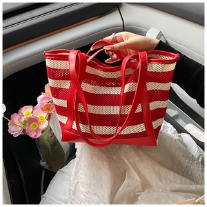 Detail of red and white striped crochet tote bag with durable leather trim in a car setting