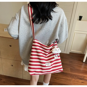 Detail of red and white striped canvas tote bag with plush cloud charm and wide strap