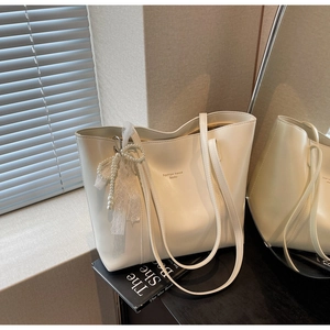 Detail of white PU leather tote bag with pearl lace bow and embossed fashion text