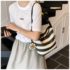 Detail of striped woven bucket bag featuring wooden horn button and sunflower charm