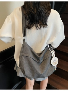 Spacious dark grey denim hobo bag worn by model with cute capybara charm accessory