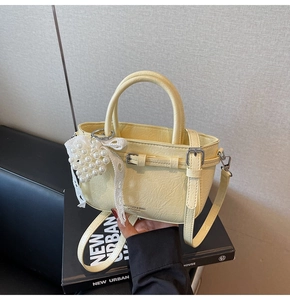 Détail d'un sac seau en cuir jaune doux avec breloque cœur en perles et nœud en dentelle