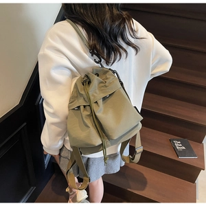 Detailed view of an army green canvas drawstring bucket backpack with cargo pockets