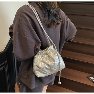 Sac seau matelassé argenté avec clous étoiles et bandoulière chaîne porté par un mannequin