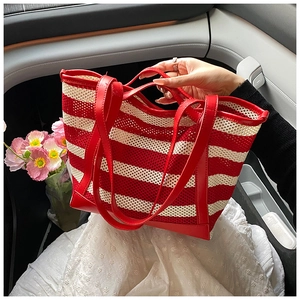 Detail of red and cream striped woven tote bag with faux leather handles in car setting