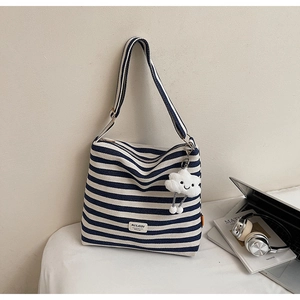 Detail of blue striped canvas tote bag with plush cloud charm and shoulder strap
