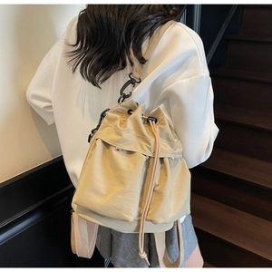 Detail view of khaki nylon bucket backpack with front flap pockets and drawstring closure