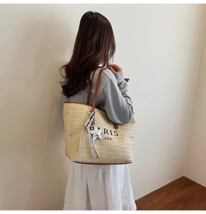 Detail of beige woven tote bag with brown leather straps and Paris Milano print