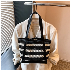 Detailed close-up of striped mesh tote bag with black leather straps on a white blazer