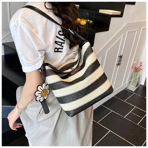 Detail of striped woven bucket bag with leather strap, bamboo clasp and flower charm